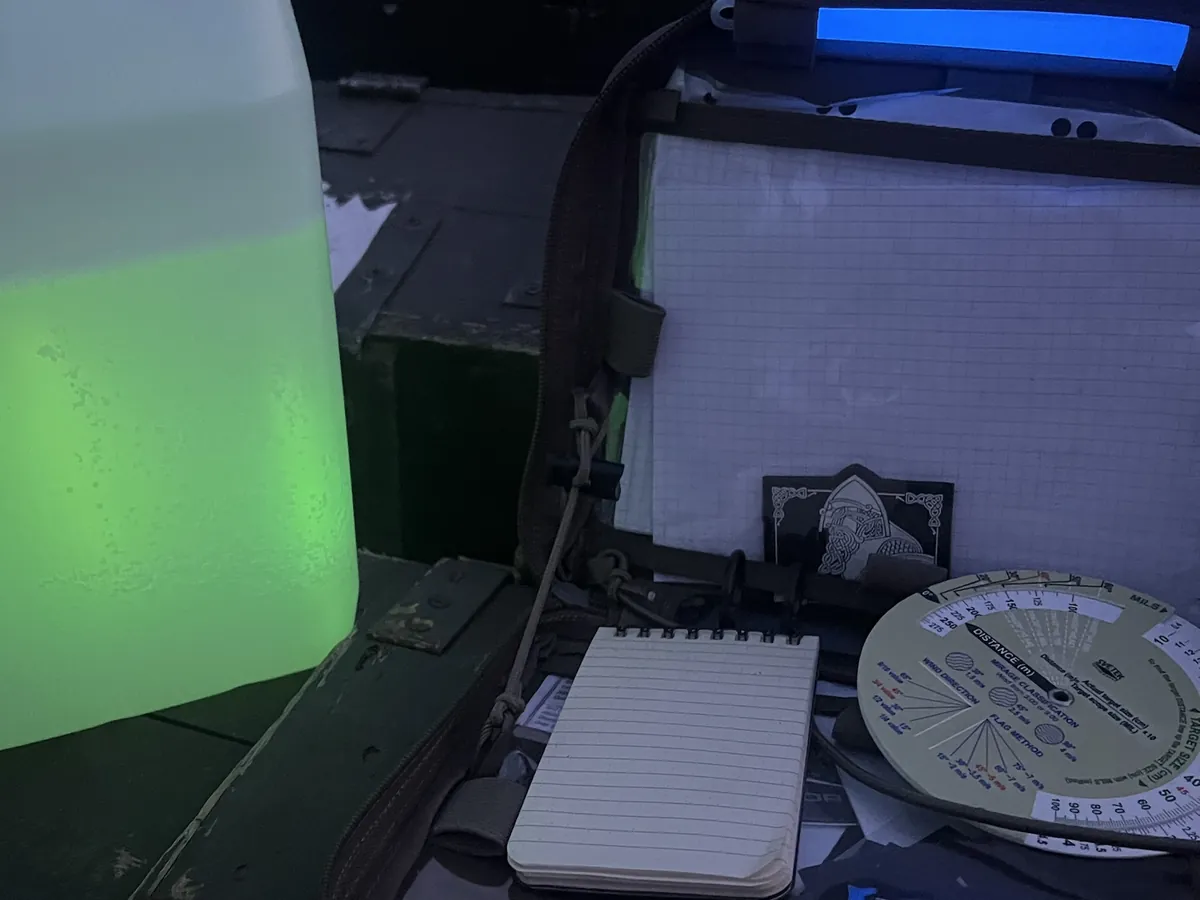 Mil-ranging disc on an ammo crate at night, lit only by chemlights